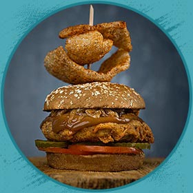 A fried chicken sandwich with pickles, tomato, and onion rings—Florida shakes and burgers style.