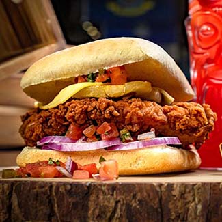 A fried chicken sandwich with cheese, onions, and diced tomatoes at Gulf Coast Burger Company.