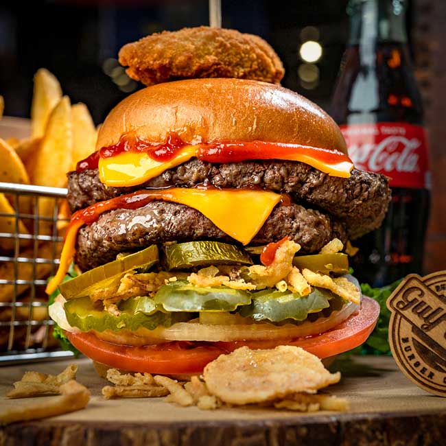 Enjoy Gulf Coast Burger Company’s double cheeseburger with fries, pickles, and a cold Coca-Cola.