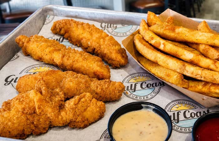 Crispy chicken tenders, seasoned fries, and dipping sauce with Gulf Coast branding in Florida.