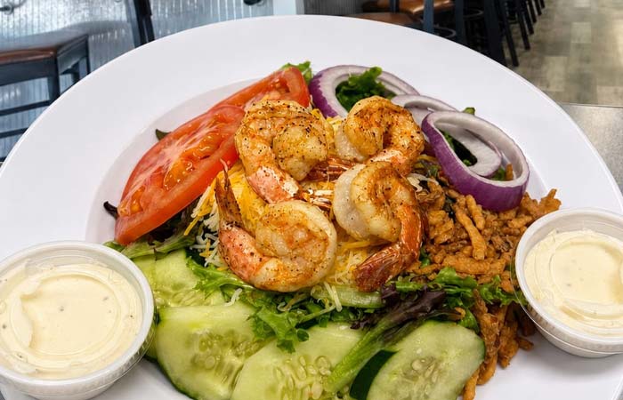 Salad with shrimp, sliced tomatoes, cucumbers, red onions, cheese—perfect for any seafood lover.