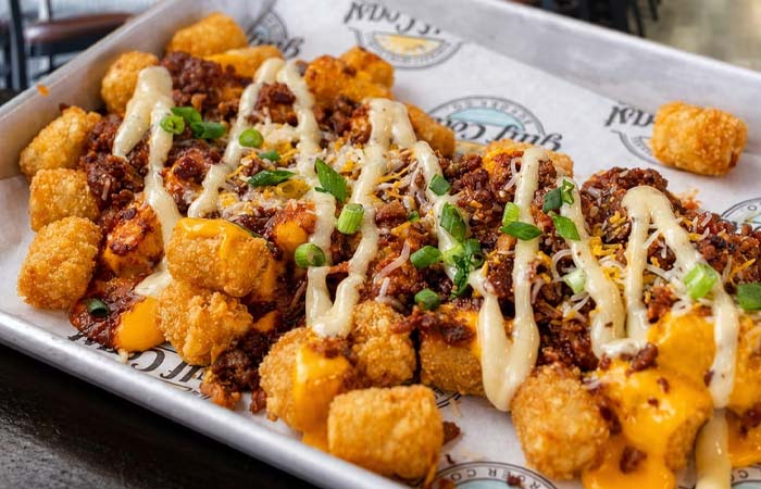 Tater tots covered in cheese, chili, and more—served Gulf Coast Burger Company style on a tray.