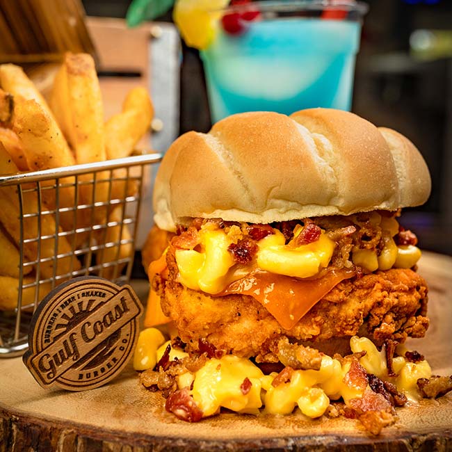 Fried chicken sandwich with mac and cheese, fries, and a blue drink at a Florida restaurant.