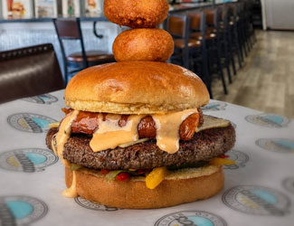 Cheeseburger with sauce, hot dog, two onion rings stacked at Gulf Coast Burger Company restaurant.